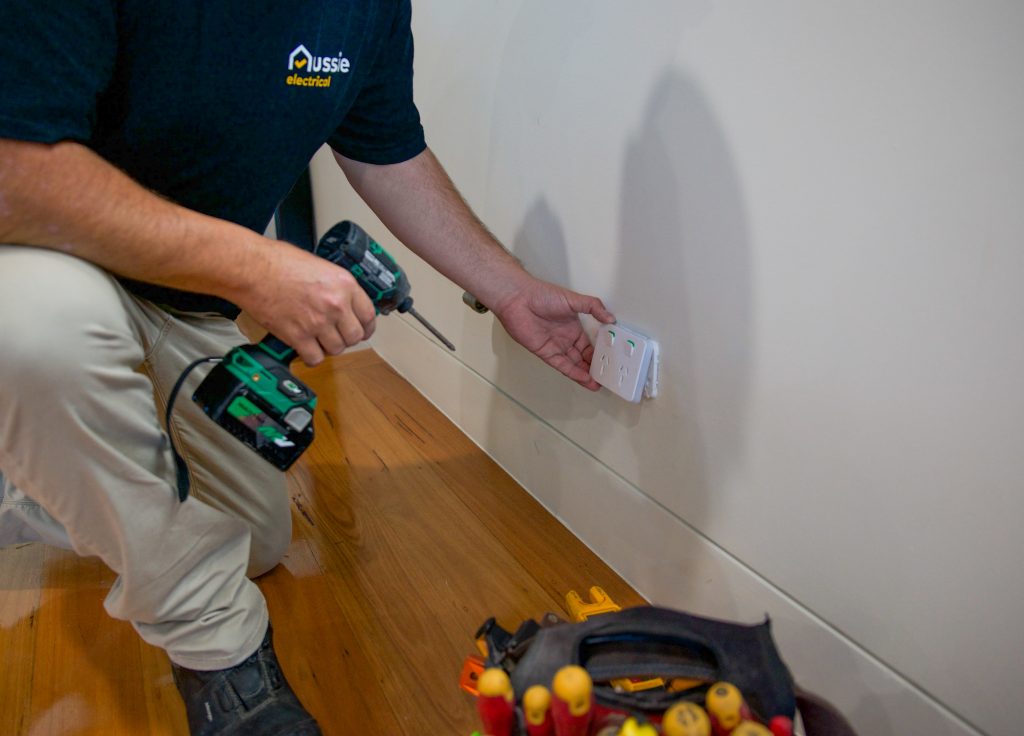 An individual is shown in the process of installing an electrical socket.